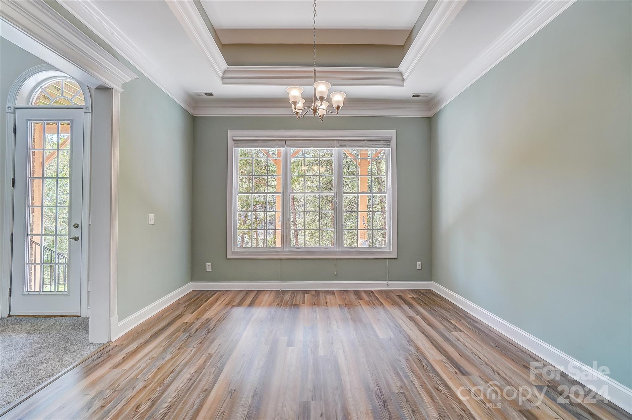 922 Cove Point Lane Tega Cay, SC 29708 - Photo 35 of 48 an empty room with wooden floor chandelier and windows