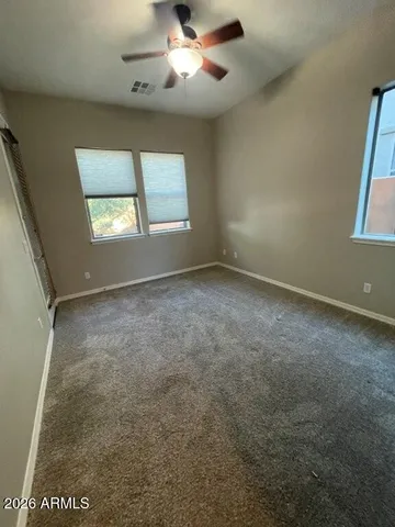 en empty room with windows and ceiling fan
