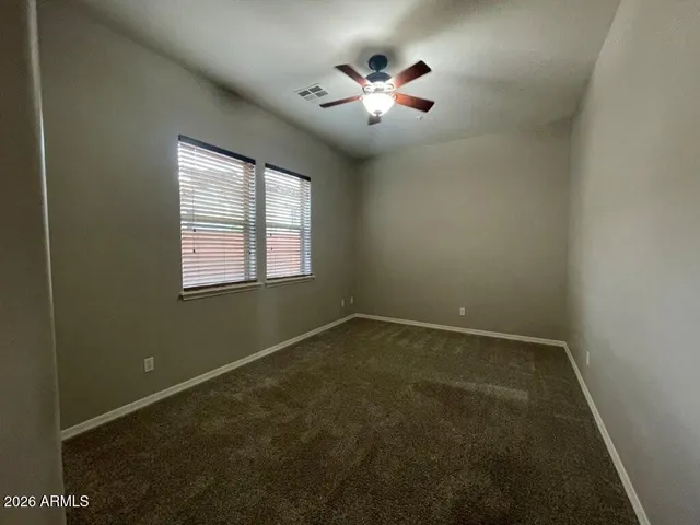 an empty room with chandelier fan and windows