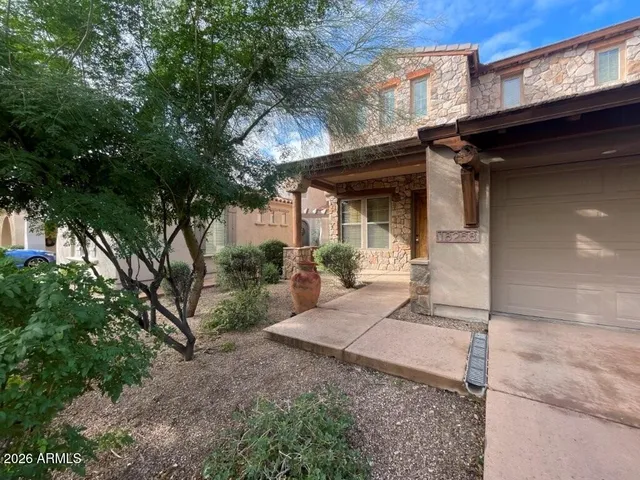 a view of a house with a small yard and large trees