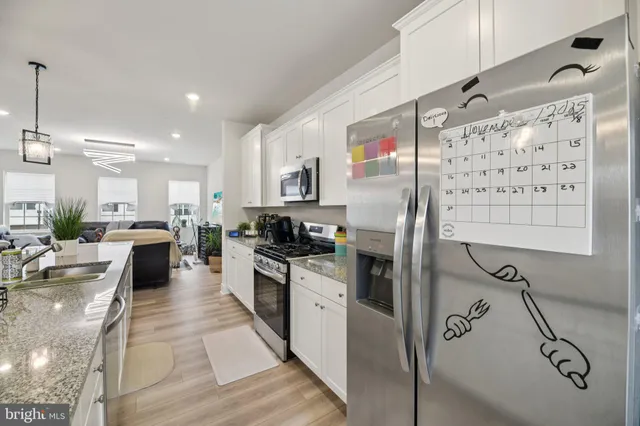 a kitchen with granite countertop a refrigerator a sink and white cabinets