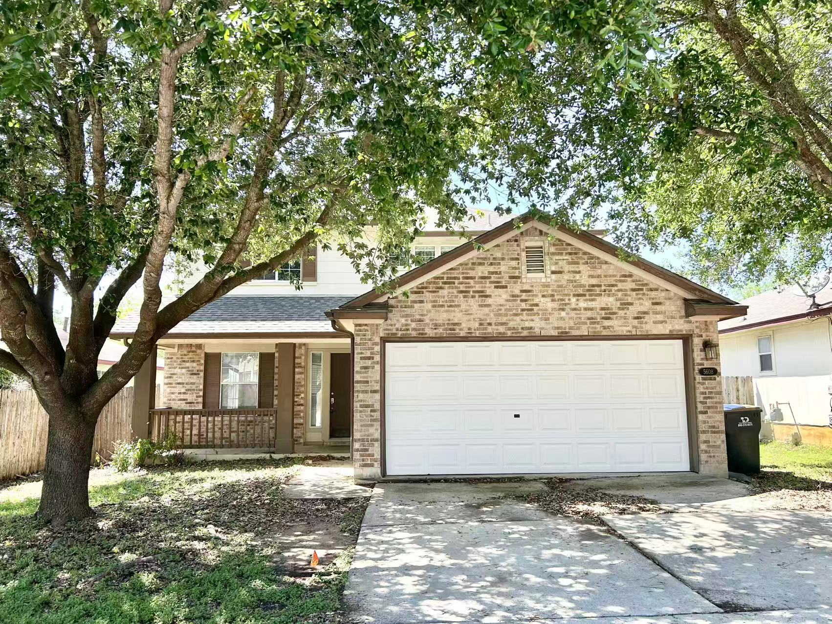5608 Netleaf Road Austin, TX 78724 - Photo 1 of 26 A charming two-story residence with a classic brick facade and inviting front porch, set against a backdrop of mature shade trees.