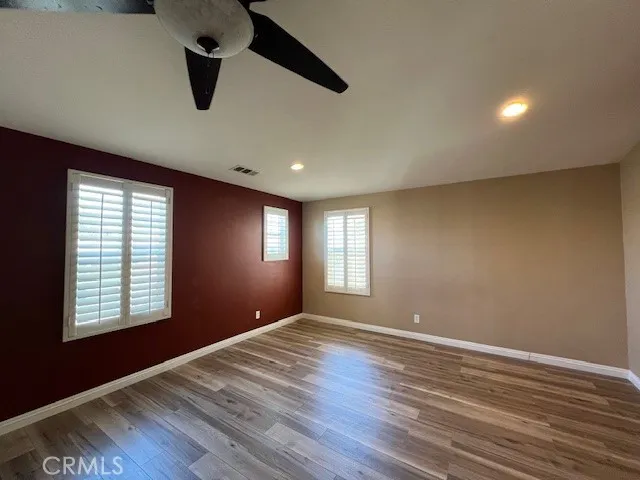 a view of empty room with wooden floor and fan