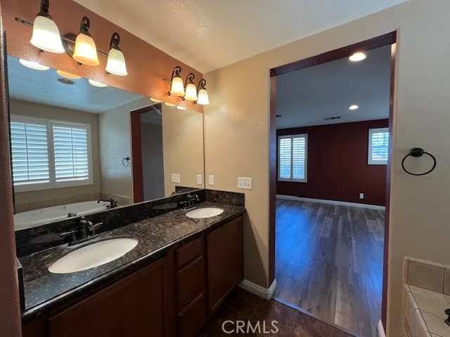 a bathroom with a granite countertop sink a light fixture and a mirror