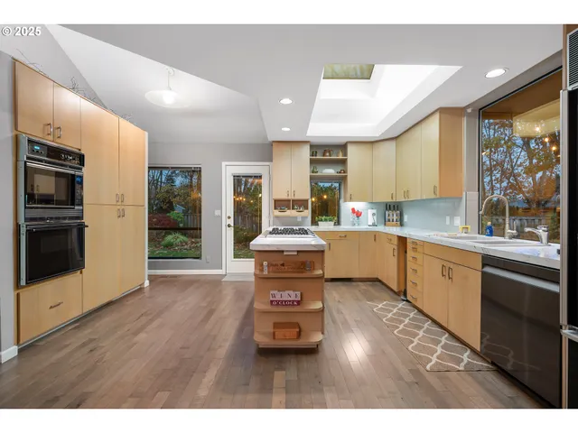 a kitchen with stainless steel appliances granite countertop a stove a sink dishwasher and a refrigerator with wooden floor