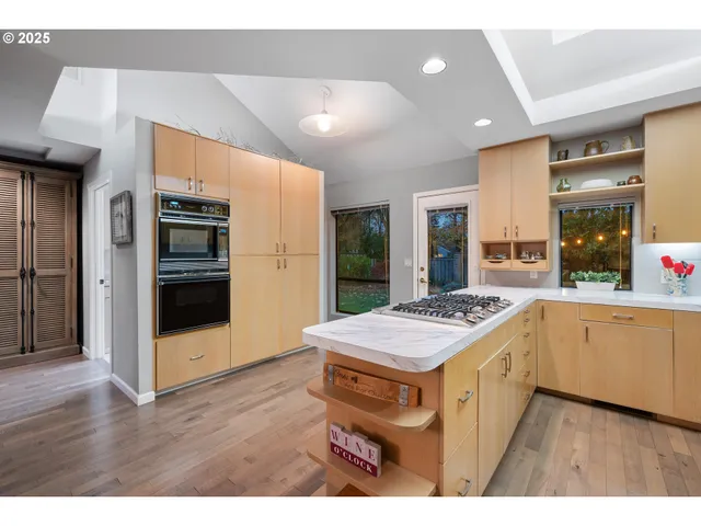 a kitchen with stainless steel appliances granite countertop a stove a refrigerator a sink and white cabinets with wooden floor