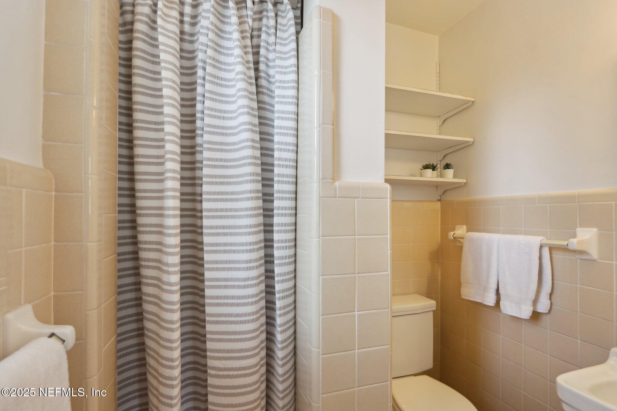 3831 Rogero Road Jacksonville, FL 32277 - Photo 17 of 33 a bathroom with a toilet and a shower curtain