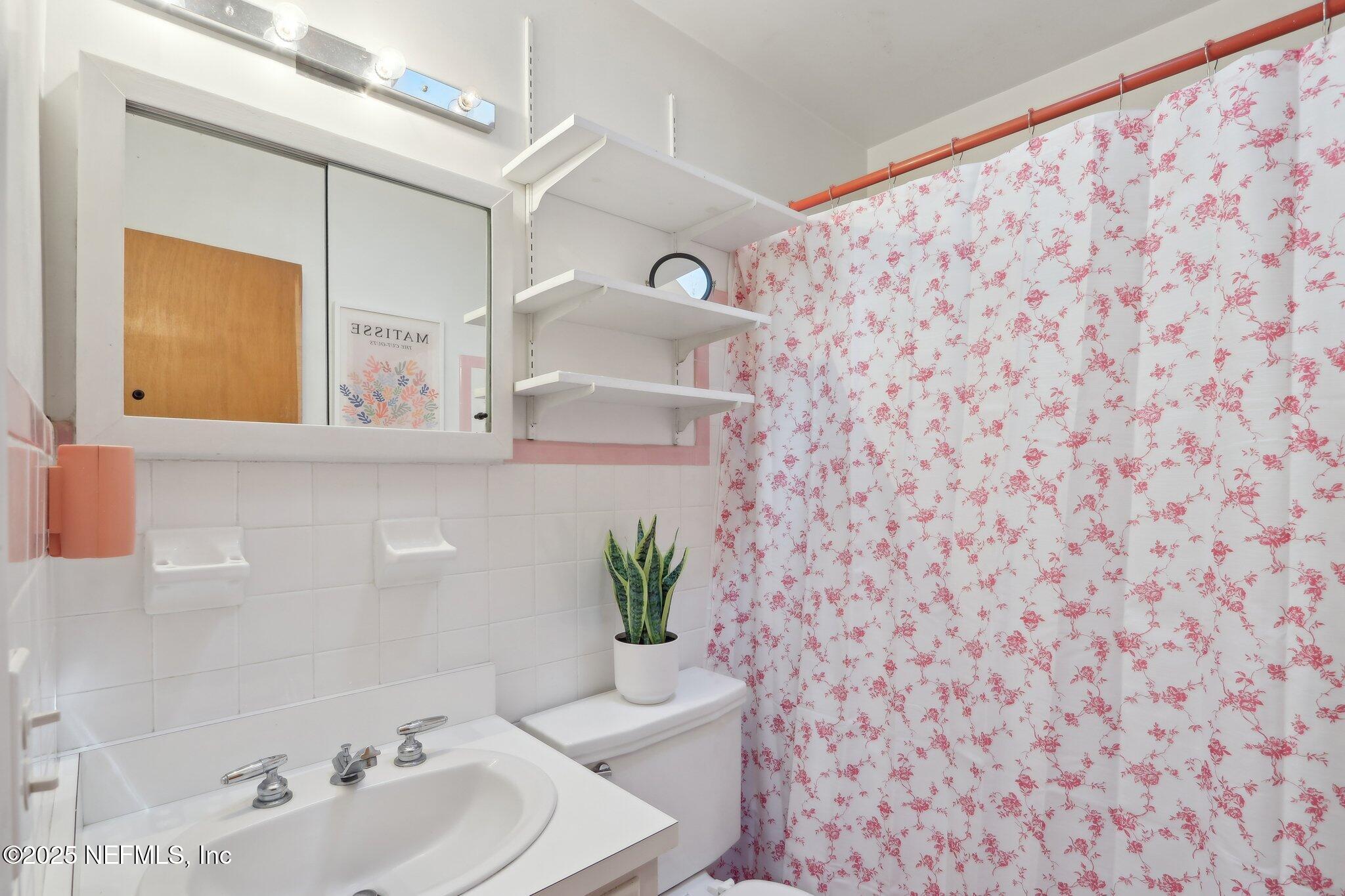 3831 Rogero Road Jacksonville, FL 32277 - Photo 24 of 33 a bathroom with a sink a mirror and a shower