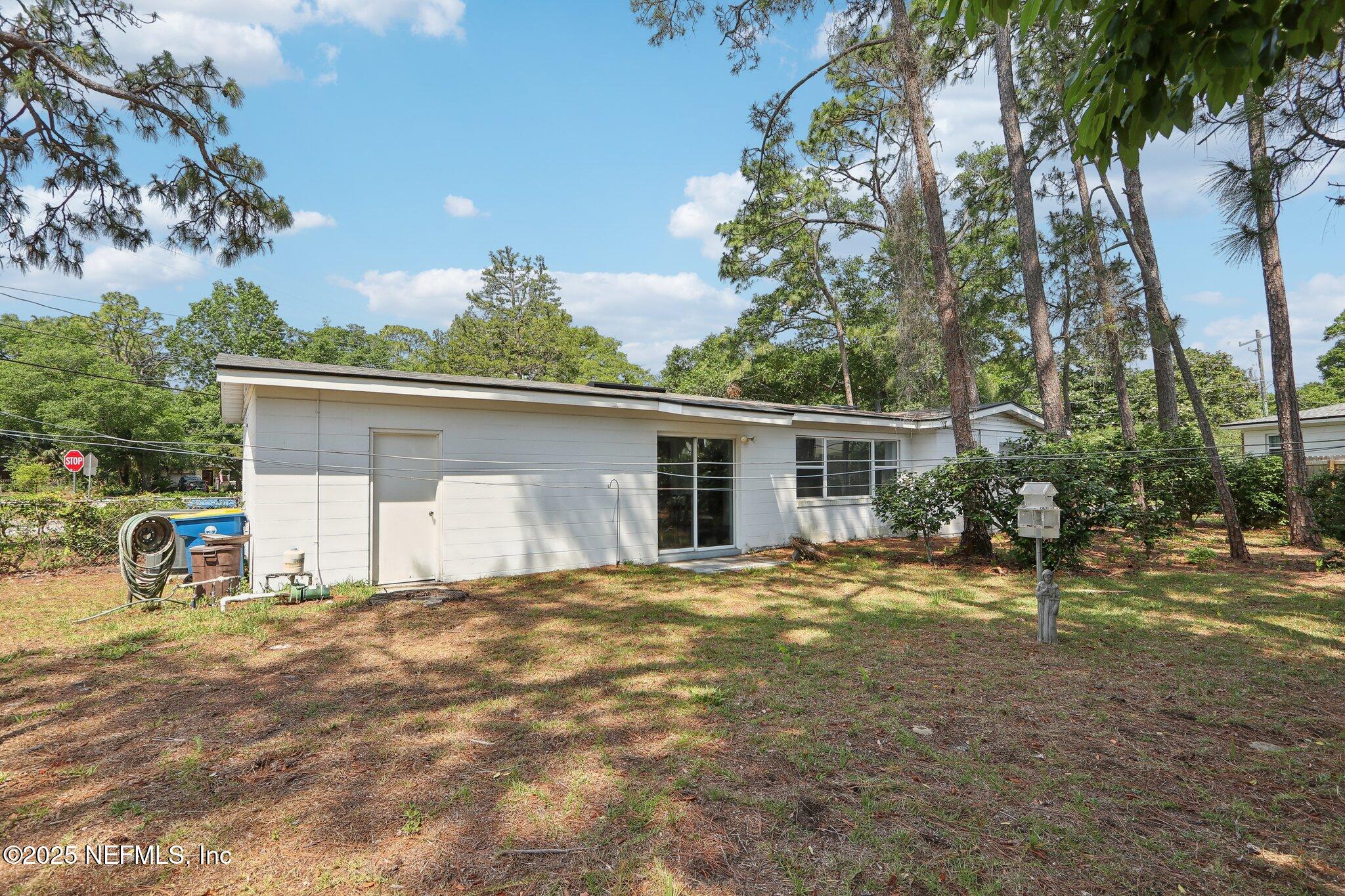 3831 Rogero Road Jacksonville, FL 32277 - Photo 27 of 33 a view of a house with a yard and lawn chairs under an umbrella