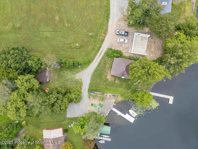 an aerial view of residential house with outdoor space and trees all around