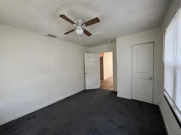 an empty room with windows and fan