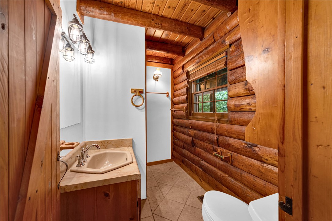237 Spring Valley Road Liberty, SC 29657 - Photo 13 of 50 A rustic bathroom with log walls and a wooden ceiling offers cozy comfort.