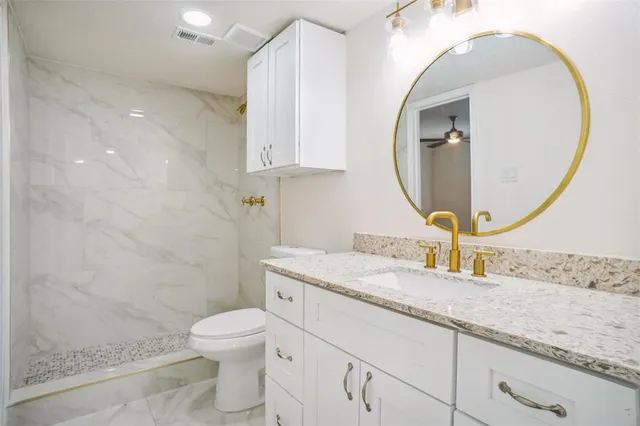 a bathroom with a granite countertop toilet a sink and a mirror