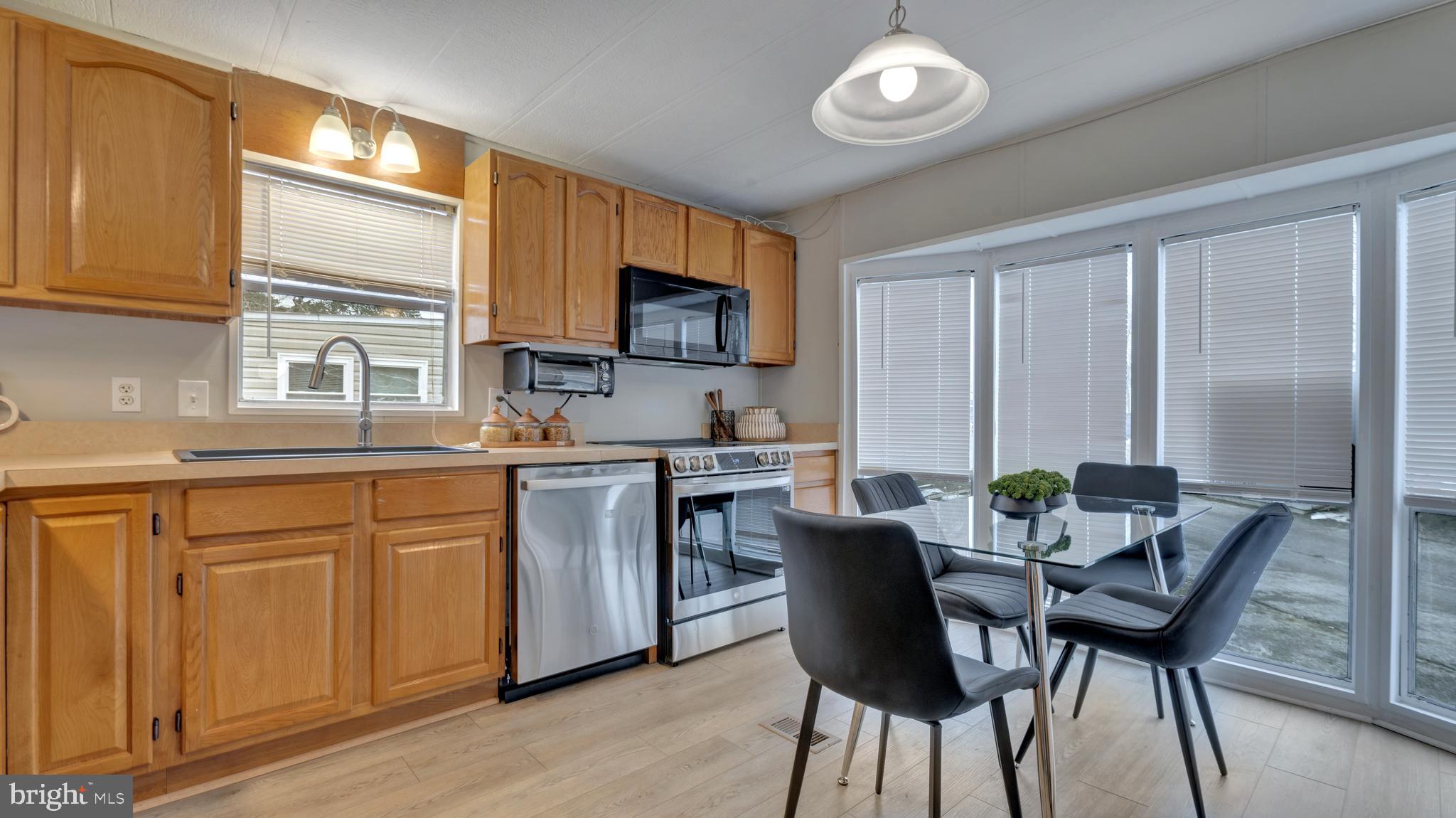 276 5th Street Lothian, MD 20711 - Photo 6 of 18 a kitchen with stainless steel appliances granite countertop a stove top oven a sink dishwasher a dining table and chairs with wooden floor