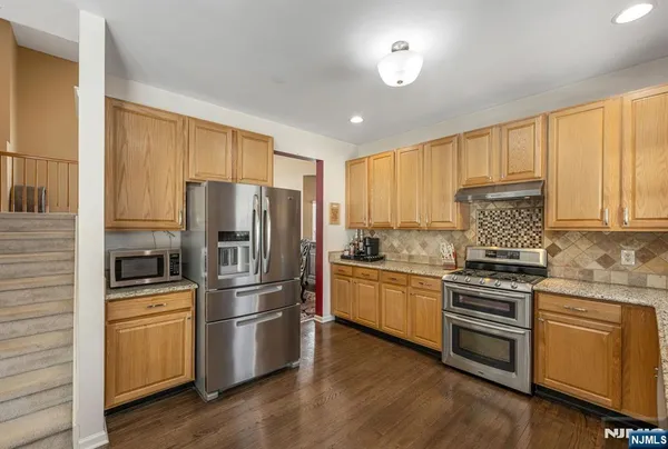 a kitchen with granite countertop stainless steel appliances and wooden floor