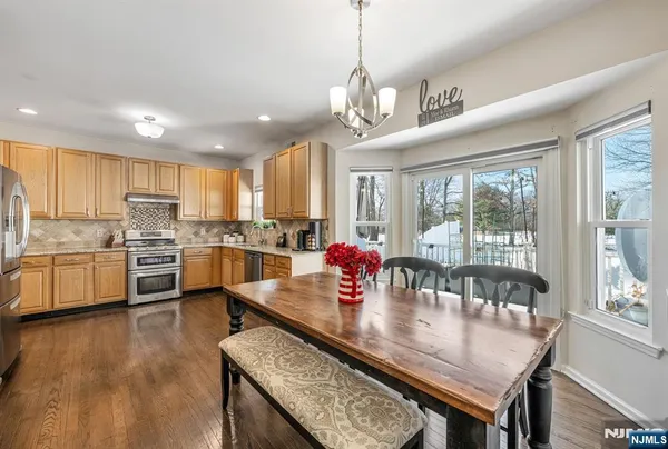 a kitchen with stainless steel appliances granite countertop a stove top oven a sink dishwasher a dining table and chairs with wooden floor