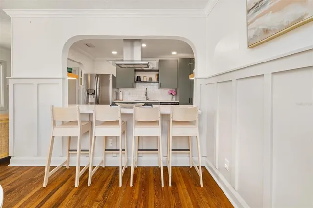 a living room with white furniture and kitchen view
