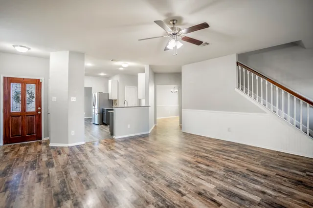 a view of a hallway with wooden floor and a kitchen