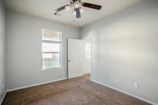 an empty room with windows and ceiling fan