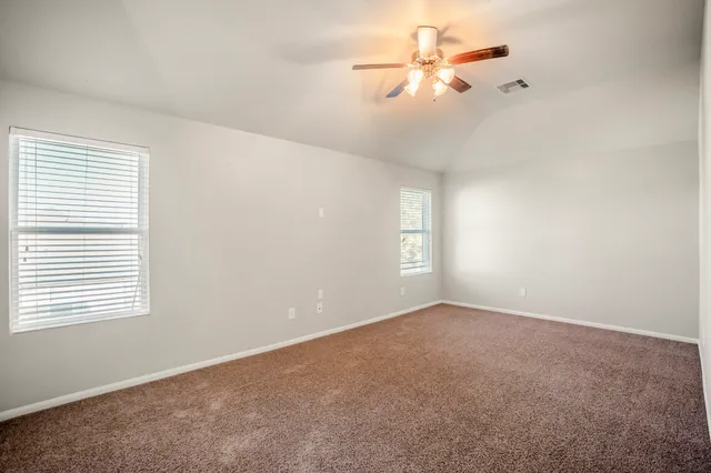 an empty room with windows and fan