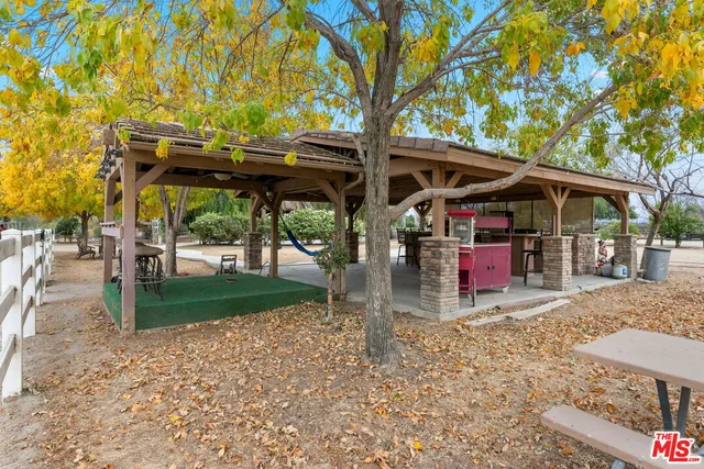 a view of a patio with table and chairs under an umbrella with a large tree