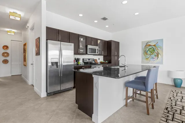 a kitchen with stainless steel appliances kitchen island granite countertop a refrigerator and a stove top oven