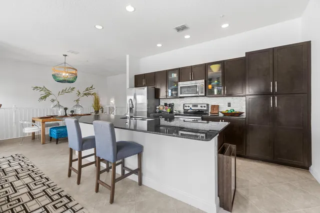 a kitchen with a sink a refrigerator and chairs