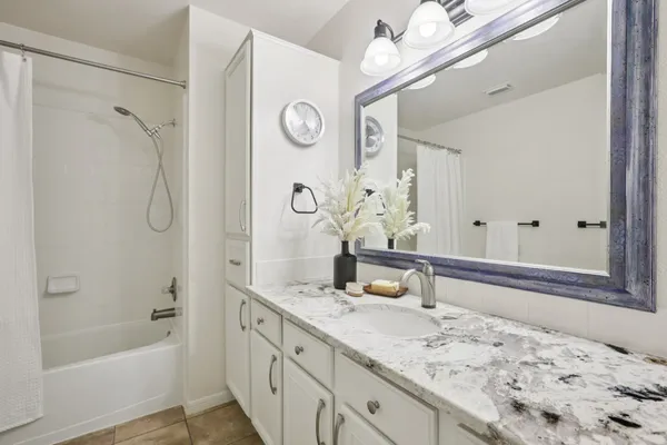 a bathroom with a granite countertop sink mirror and a bathtub