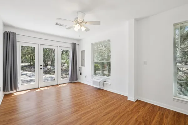 a view of an empty room with wooden floor and a window