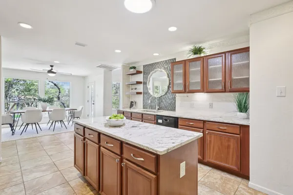 a kitchen with a sink a counter top space and living room view