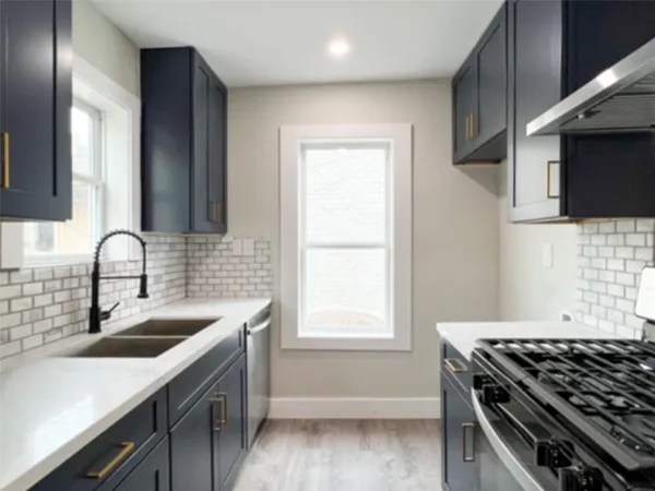 a kitchen with granite countertop a sink stove and cabinets