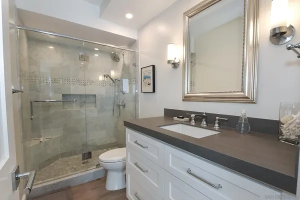 a bathroom with a granite countertop bathtub shower sink mirror and toilet