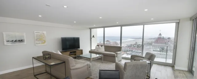 a living room with furniture a flat screen tv and a floor to ceiling window