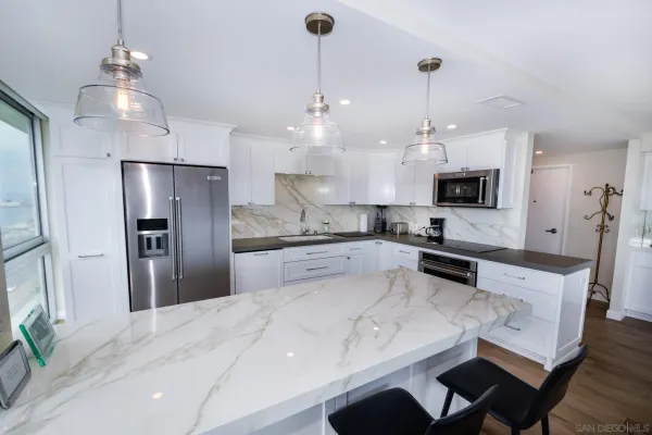 a large kitchen with cabinets a sink stainless steel appliances and chandelier