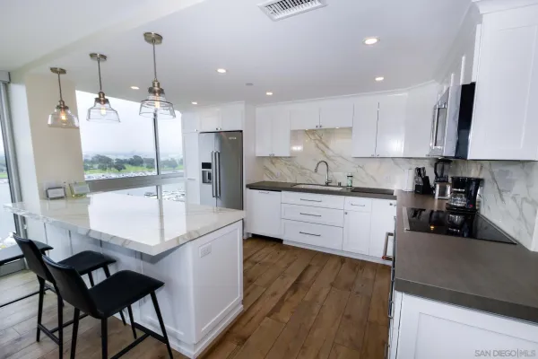 a kitchen with stainless steel appliances kitchen island granite countertop a sink a stove a refrigerator and island with wooden floor