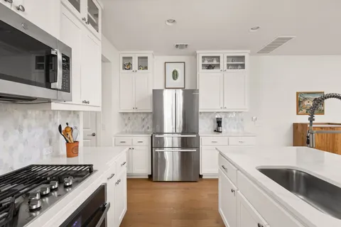 a kitchen with stainless steel appliances granite countertop a refrigerator and a stove top oven