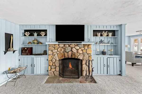 a view of an empty room with wooden floor and a fireplace