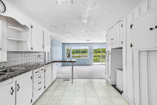 a large white kitchen with granite countertop a stove a sink dishwasher and a refrigerator