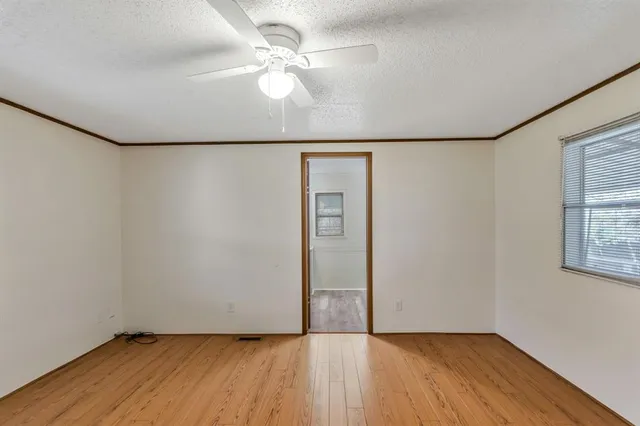 an empty room with wooden floor chandelier fan and windows
