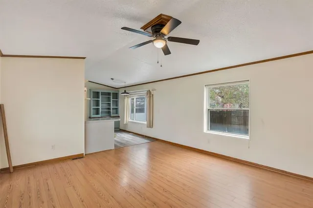 a view of an empty room with a window and wooden floor