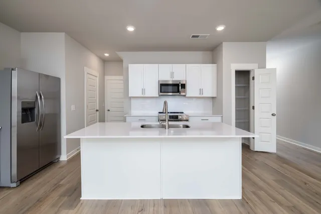 a kitchen with kitchen island a sink stainless steel appliances and cabinets