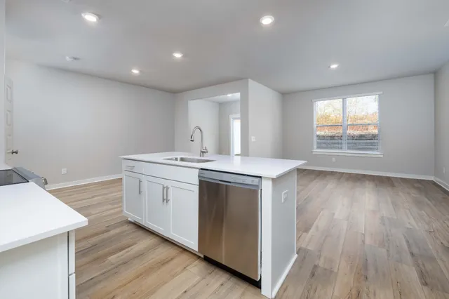 a kitchen with a sink cabinets wooden floor and a window