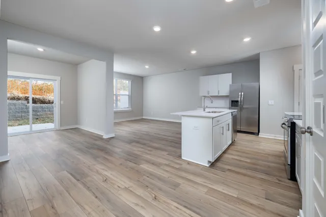 a large kitchen with stainless steel appliances granite countertop a large counter top a sink and a refrigerator