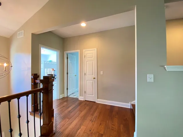 a view of a hallway with wooden floor and a living room