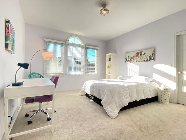 a spacious bedroom with a bed window and table