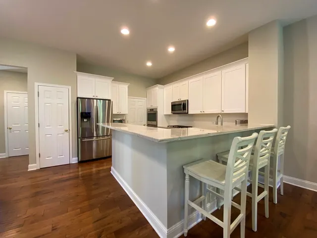 a kitchen with stainless steel appliances kitchen island granite countertop a refrigerator a stove microwave and cabinets