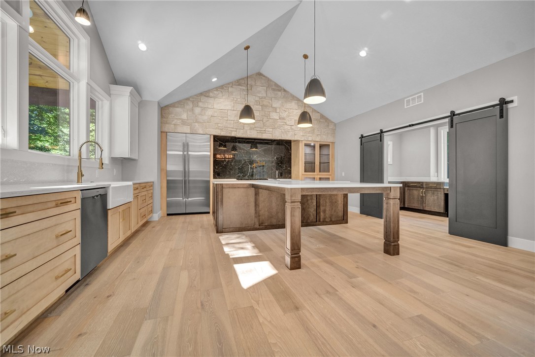 4009 Brainard Road Beachwood, OH 44122 - Photo 16 of 50 Kitchen featuring light hardwood floors, a barn door, a kitchen island, high vaulted ceiling, and dishwasher