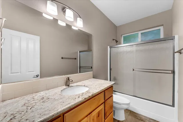 a bathroom with a granite countertop sink mirror vanity and toilet