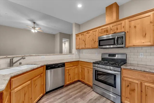 a kitchen with stainless steel appliances granite countertop a stove a sink and a microwave