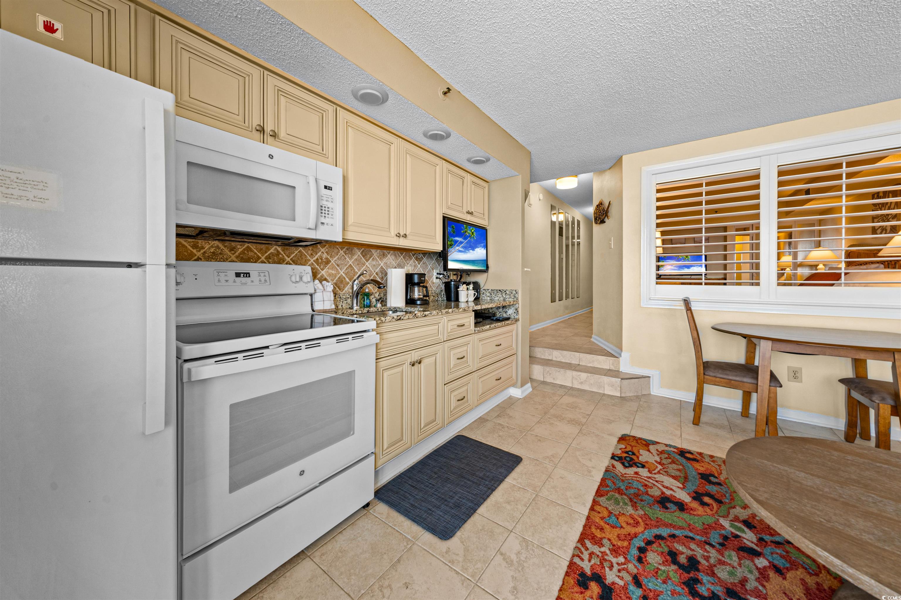 5308 North Ocean Boulevard, Unit 2006 Myrtle Beach, SC 29577 - Photo 11 of 37 Kitchen with white appliances, cream cabinets, tile flooring, granite countertops, and tile backsplash